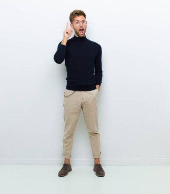 Genç bir vücut adamı bir fikri fark ettikten sonra mutlu ve heyecanlı bir dahi gibi hissediyor. Neşeli bir şekilde parmağını kaldırıyor. Evreka! beyaz arkaplan