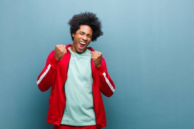 Genç siyah sporcu muzaffer bir şekilde bağırıyor, gülüyor, mutlu ve heyecanlı hissediyor ve grunge duvarına karşı başarıyı kutluyor.