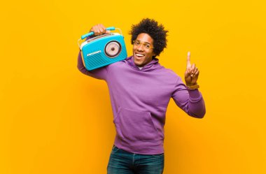 Turuncu B 'ye karşı klasik radyosu olan genç Afro-Amerikan bir adam.