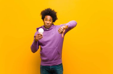 Portakala karşı ampulü olan genç Afrikalı Amerikalı adam.