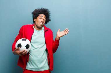 Genç siyah bir adam futbol topuyla mavi grunge wa 'ya karşı.