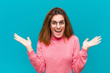 Genç, güzel bir kadın mutlu, heyecanlı, şaşırmış ya da şaşırmış, gülümseyen ve hayrete düşmüş.