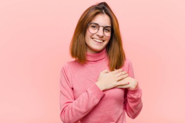 Genç, güzel bir kadın romantik, mutlu ve aşık, neşeyle gülümseyen ve pembe arka planda el ele tutuşan