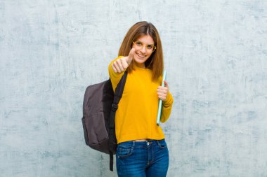 Genç bayan kendini gururlu, kaygısız, kendinden emin ve mutlu hissediyor. Grunge Wall arka planına karşı olumlu gülümsüyor.