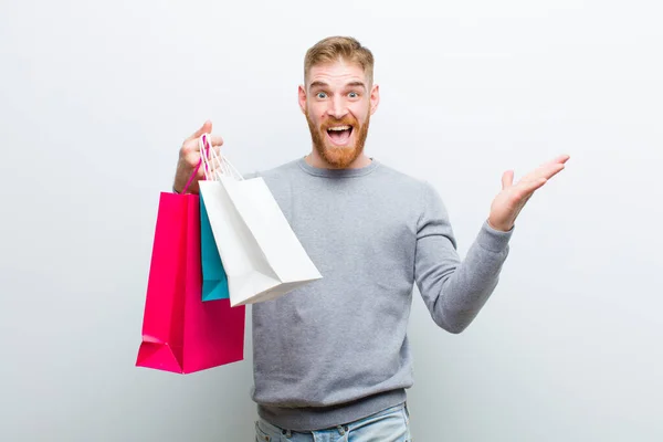 Jovem Homem Cabeça Vermelha Com Sacos Compras Contra Fundo Branco — Fotografia de Stock