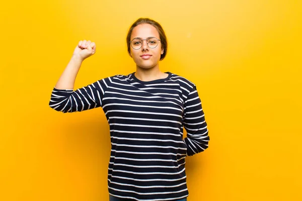 여성은 진지하고 강하고 반항적 주먹을 항의하거나 오렌지 배경에 대항하는 혁명을 — 스톡 사진