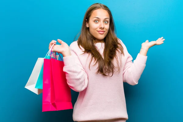 Giovane donna con borse della spesa sullo sfondo blu — Foto Stock