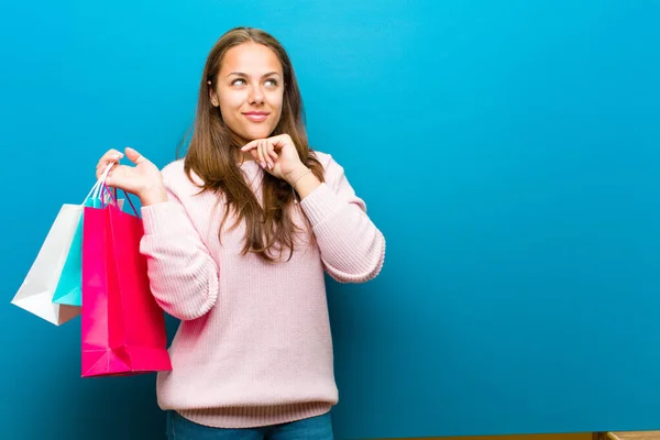 青い背景にショッピングバッグを持つ若い女性 — ストック写真