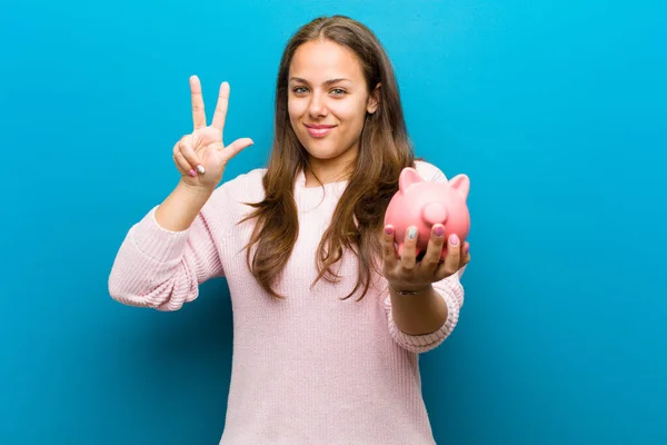 Jonge vrouw met een Piggy Bank tegen blauwe achtergrond — Stockfoto