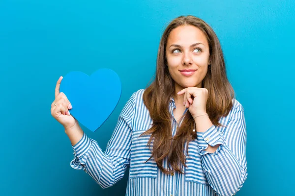 Jeune femme avec une forme de coeur sur fond bleu — Photo