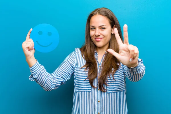 Jonge vrouw met een smiley gezicht tegen blauwe achtergrond — Stockfoto