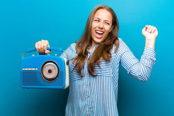 Mujer joven con una radio vintage sobre fondo azul — Foto de Stock