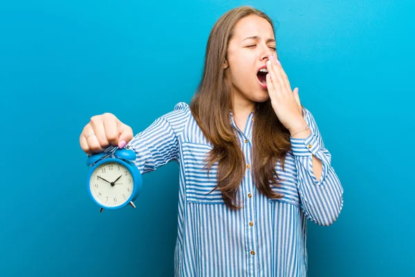 青い背景に対する目覚まし時計を持つ若い女性 — ストック写真