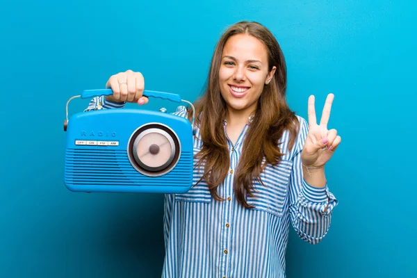 Mujer joven con una radio vintage sobre fondo azul — Foto de Stock