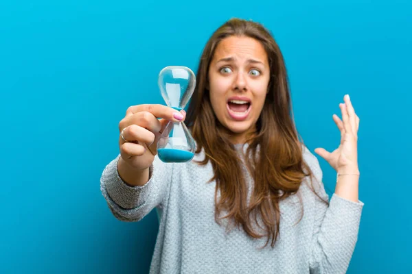 Mujer joven con temporizador de arena sobre fondo azul — Foto de Stock