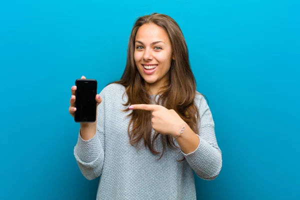 Mladá žena s mobilním telefonem na modrém pozadí — Stock fotografie