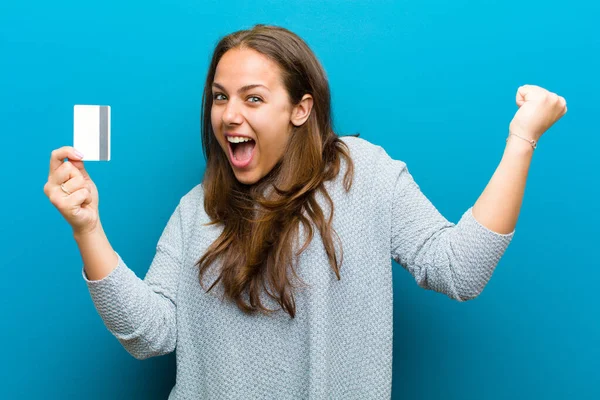 Giovane donna con una carta di credito su sfondo blu — Foto Stock