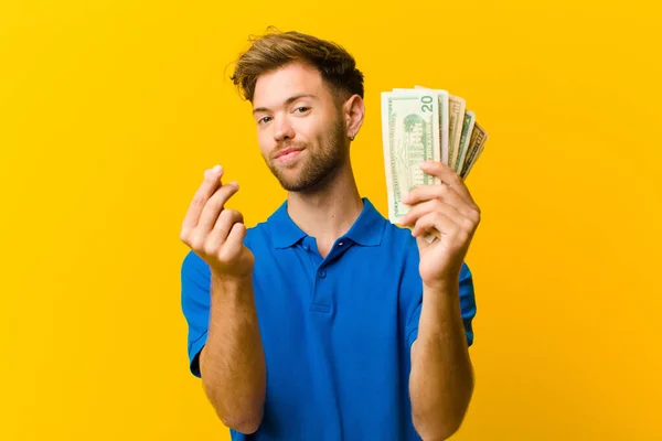 Jongeman Met Bankbiljetten Tegen Oranje Achtergrond — Stockfoto