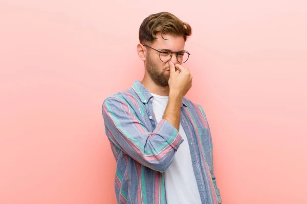 Junger Mann Angewidert Hält Nase Vor Rosafarbenem Hintergrund Keinen Unangenehmen — Stockfoto