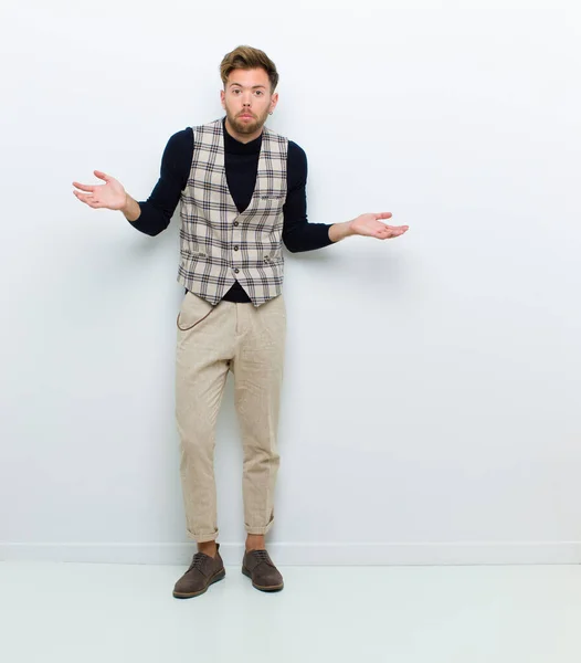 young full body man feeling clueless and confused, having no idea, absolutely puzzled with a dumb or foolish look against white background