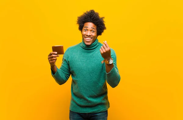 Mladý africký Američan s peněženkou proti oranžové pozadí — Stock fotografie