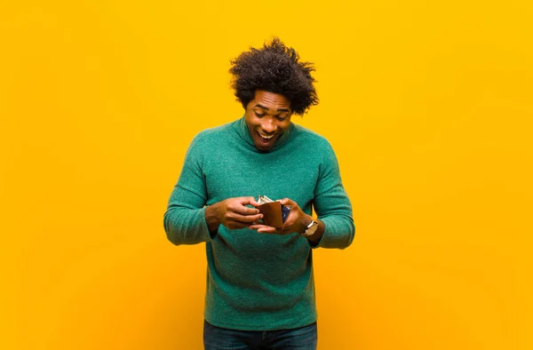 Young african american man with a wallet against orange backgrou — ストック写真