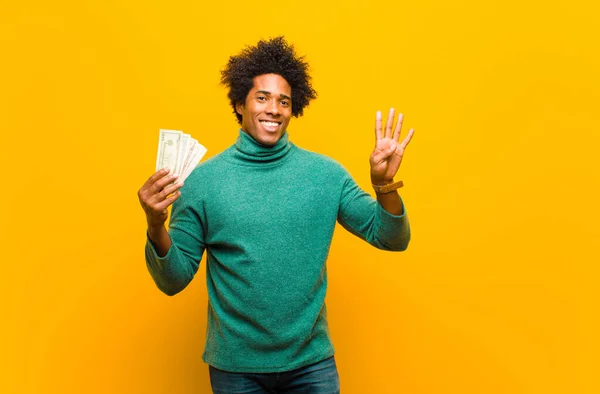 Joven afroamericano hombre con billetes de dólar contra naranja espalda —  Fotos de Stock