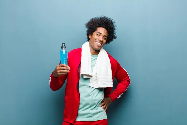 Młody czarny człowiek z napój sportowy przeciwko niebieski grunge ściany — Zdjęcie stockowe