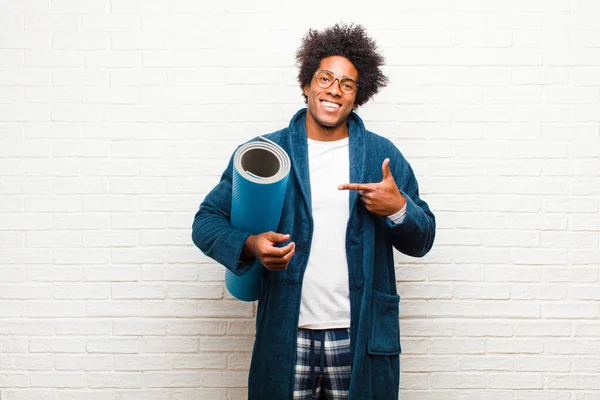 Ung svart man i pyjamas med yogamatta — Stockfoto