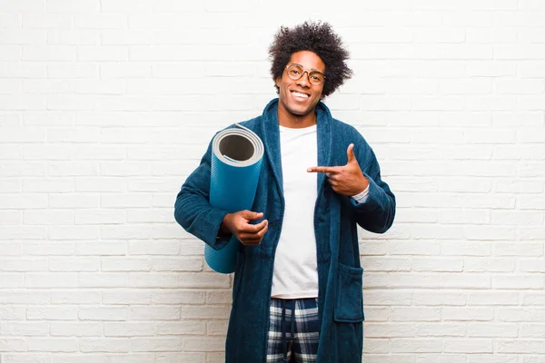 Joven negro usando pijama con una esterilla de yoga — Foto de Stock