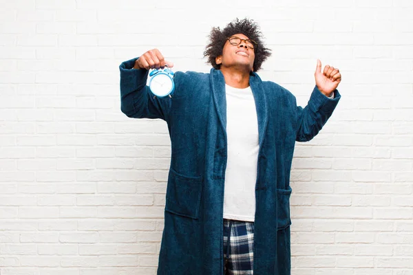 young black man wearing pajamas with an alarm clock