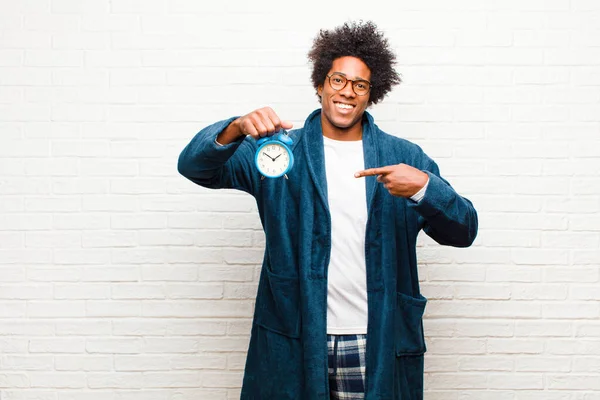 young black man wearing pajamas with an alarm clock