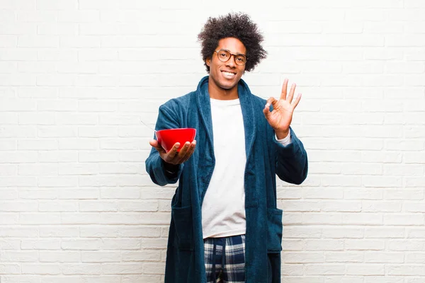 Ung svart man bär pyjamas med en frukost skål mot br — Stockfoto