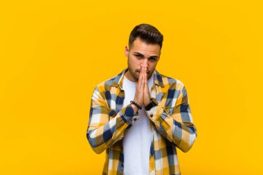 Genç İspanyol adam endişeli, umutlu ve dindar hissediyordu. Avuçlarına bastırılmış, turuncu duvara karşı af dileyen sadık bir şekilde dua ediyordu.