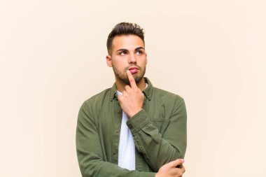 Şaşırmış, gergin, endişeli ya da korkmuş bakışları olan genç İspanyol adam izole edilmiş arka plana karşı fotokopi alanına doğru bakıyor.