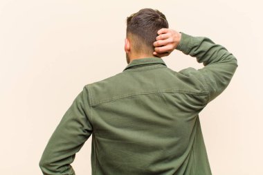 Genç İspanyol adam düşünüyor ya da şüphe ediyor, kafasını kaşıyor, şaşkın ve şaşkın hissediyor, izole edilmiş arka plana karşı arka ya da arka plan