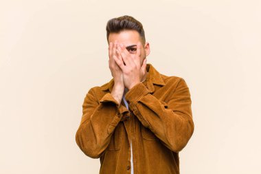 Latin kökenli genç bir adam korkmuş ya da utanmış hissediyor. Gözleriyle bakıyor ya da dikizliyor. Elleri yarı kapalı, soyutlanmış arka plana bakıyor.