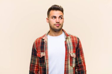 Genç İspanyol adam şok olmuş, mutlu, şaşırmış ve şaşırmış hissediyor. Ağzı açık bir şekilde izole edilmiş arka plana bakıyor.