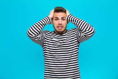 Genç İspanyol adam mutlu, kaygısız, arkadaş canlısı ve rahat görünüyor. Hayattan ve başarıdan keyif alıyor, mavi arka plana karşı pozitif bir tutum sergiliyor.