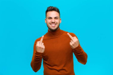 Genç İspanyol bir adam kışkırtıcı, agresif ve müstehcen hissediyor. Mavi arka plana karşı isyankar bir tavırla orta parmağını hareket ettiriyor.