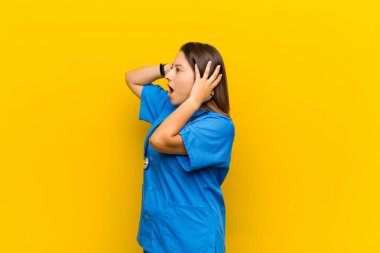 Korkunç bir hata yüzünden dehşete düşmüş ve şok olmuş bir halde, sarı duvara yaslanmış ellerini kaldırarak.