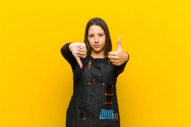 Kuaför kadın kafası karışık, bilgisiz ve kararsız hissediyor, iyi ve kötü seçenekleri farklı seçeneklerle tartıyor veya turuncu arka planla karşılaştırıyor.