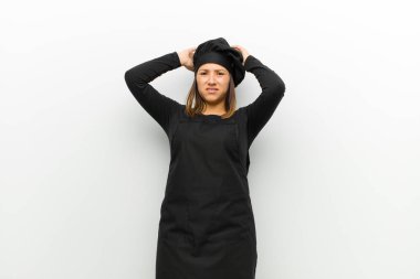 Aşçı kadın hayal kırıklığına uğramış ve sinirlenmiş, başarısızlıktan bıkmış, beyaz arka plana karşı sıkıcı ve sıkıcı görevlerden bıkmış.