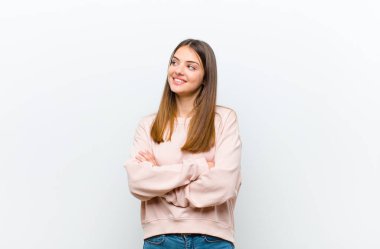 Genç, güzel bir kadın kendini mutlu, gururlu ve umutlu hissediyor, merak ediyor ya da düşünüyor, beyaz arka planda çapraz kollarla fotokopi çekmeyi bekliyor.