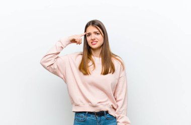 Genç, güzel bir kadın kafası karışık ve şaşkın hissediyor. Deli, deli ya da beyaz arka plana karşı aklını kaçırmış olduğunu gösteriyor.