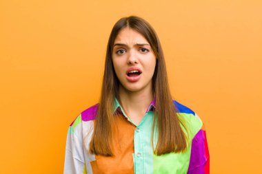 Genç ve güzel bir kadın dehşete kapılmış ve şok olmuş hissediyor, ağzı ardına kadar açık ve şaşırmış bir şekilde düz arkaplandan izole edilmiş.