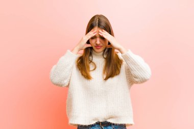 Genç ve güzel bir kadın stresli ve hayal kırıklığına uğramış görünüyor. Baskı altında çalışıyor ve pembe arka planda sorunlar yaşıyor.