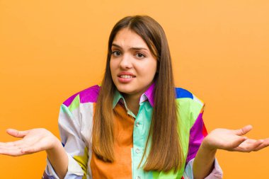 Genç ve güzel bir kadın bilgisiz ve şaşkın hissediyor, hangi seçeneği seçeceğinden emin değil, düz arkaplan karşısında izole edilmiş olarak merak ediyor.