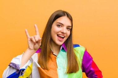 Genç, güzel bir kadın kendini mutlu, eğlenceli, kendinden emin, pozitif ve isyankar hisseder. Düz arkaplanda elle izole edilmiş kaya ya da heavy metal tabelaları yapar.