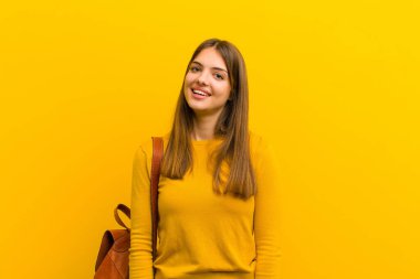 Büyük, dostane, kaygısız bir gülümsemesi olan genç ve güzel bir kadın. Olumlu, rahat ve mutlu görünüyor. Turuncu arka planda takılıyor.